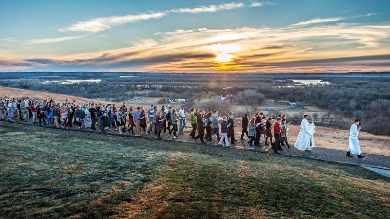 Young people following a Palm Sunday processional at sunset.